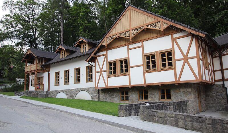 Zabytkowy odrestaurowany drewniany budynek pomalowany na biało z brązową dekoracją