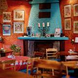 Wnętrze kawiarni Cafe Pencjonat w Lackoronie z pomalowanym na niebiesko kominkiem, czerwonymi ścianami, na których wiszą obrazy, przy jednym z okręgłych stolikó siedzi kilkuletni chłopiec