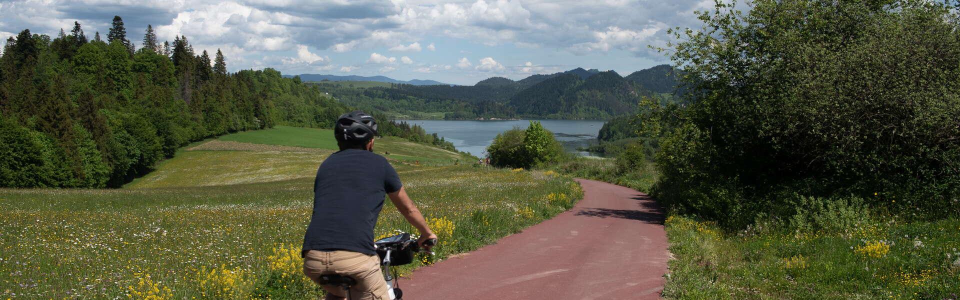 Rowerzysta z sakwami na trasie rowerowej w tle widać jezioro